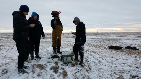 Group of 4 standing in a snowy Alaska field