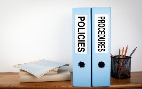 Two blue binders stood on end with labels on the spine that say "policies" and "procedures."