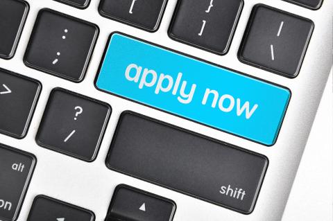 A computer keyboard with an added blue button that says apply now.